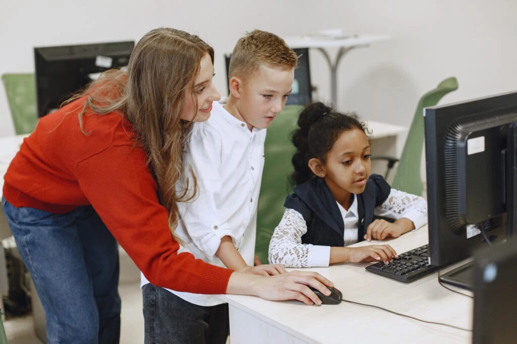 Technician helping a teacher and students at a computer